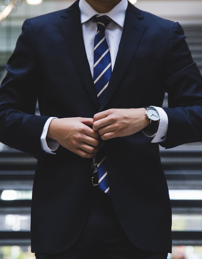 Asesor de traje azul oscuro ajustándose el saco, con reloj clásico