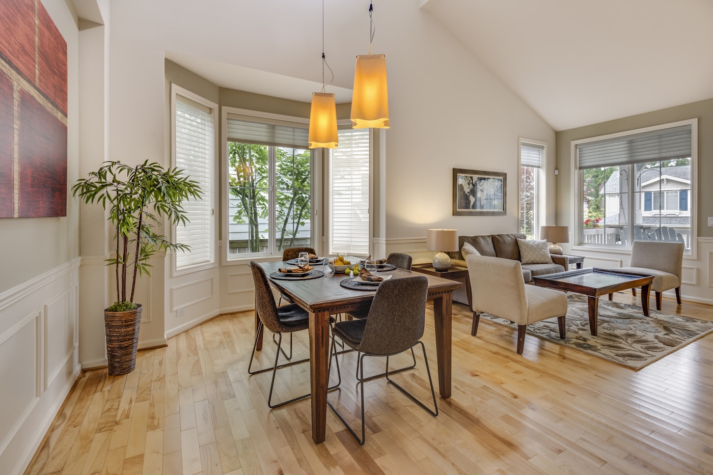 Suite con estar de techos altos, piso de madera, sillones y comedor propio iluminados por lámparas cálidas
