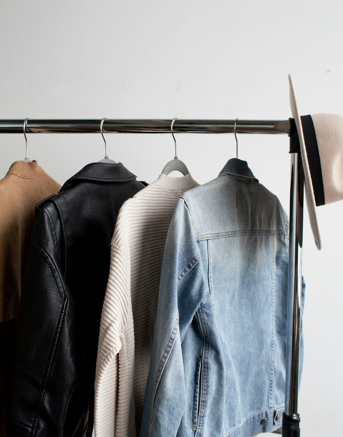 Percha minimalista del showroom con piezas seleccionadas y un sombrero de fieltro