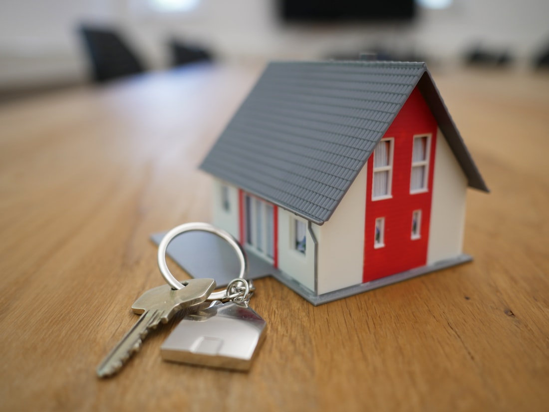 Maqueta de una casa junto a un llavero sobre una mesa de madera